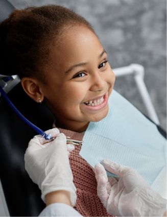Young girl grinning as a dentist placing a dental bib on her
