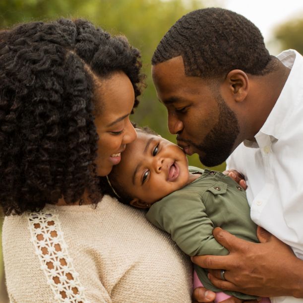 Two parents hugging and kissing their baby